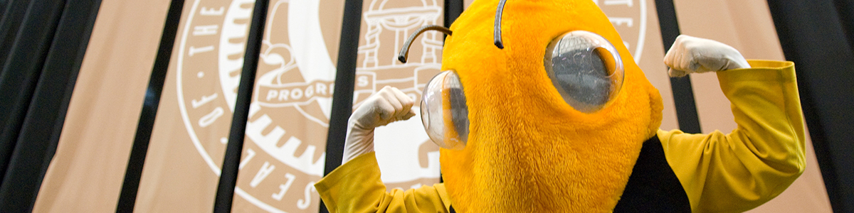 Buzz, Georgia Tech’s yellow jacket mascot, flexes in front of the Institute seal.