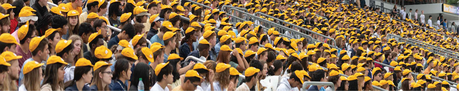 An image of a large crowd of students at Georgia Tech’s new student convocation, a first-year tradition where students gather to receive their golden “RAT caps.” The students in the image are all wearing their new hats.